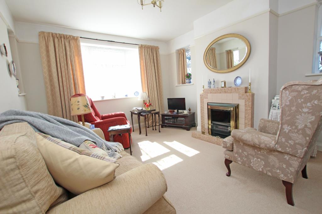 Lot: 129 - DETACHED BUNGALOW LET ON REGULATED TENANCY - Living room with window and fireplace taken August 2024